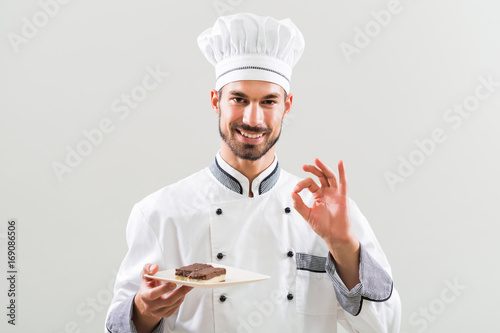 Tableau sur toile Confectioner is showing slices of cake and ok sign on gray background