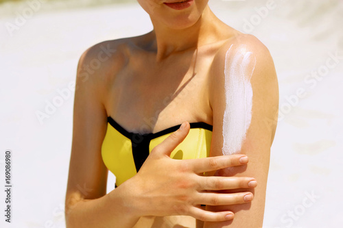 Sunscreen woman. Woman applying sunscreen on tanned skin photo