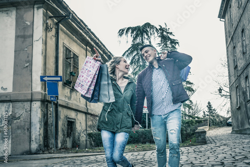 Couple in shopping together. Young couple holding hands and walking trough street.