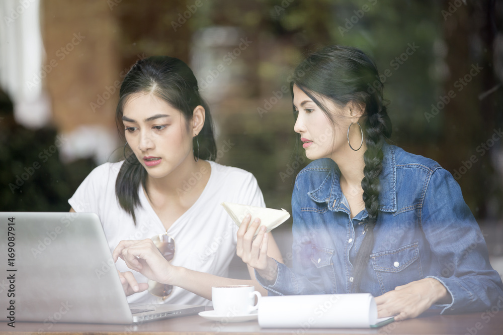 Asian Woman using Laptop for Seach Information at Cafe Together, Woman Talking with Friend while using Laptop, Woman Lifestyle Concept. Asian Woman using Laptop for Seach Information at Cafe Together, Woman Talking with Friend while using Laptop, Woman Lifestyle Concept.