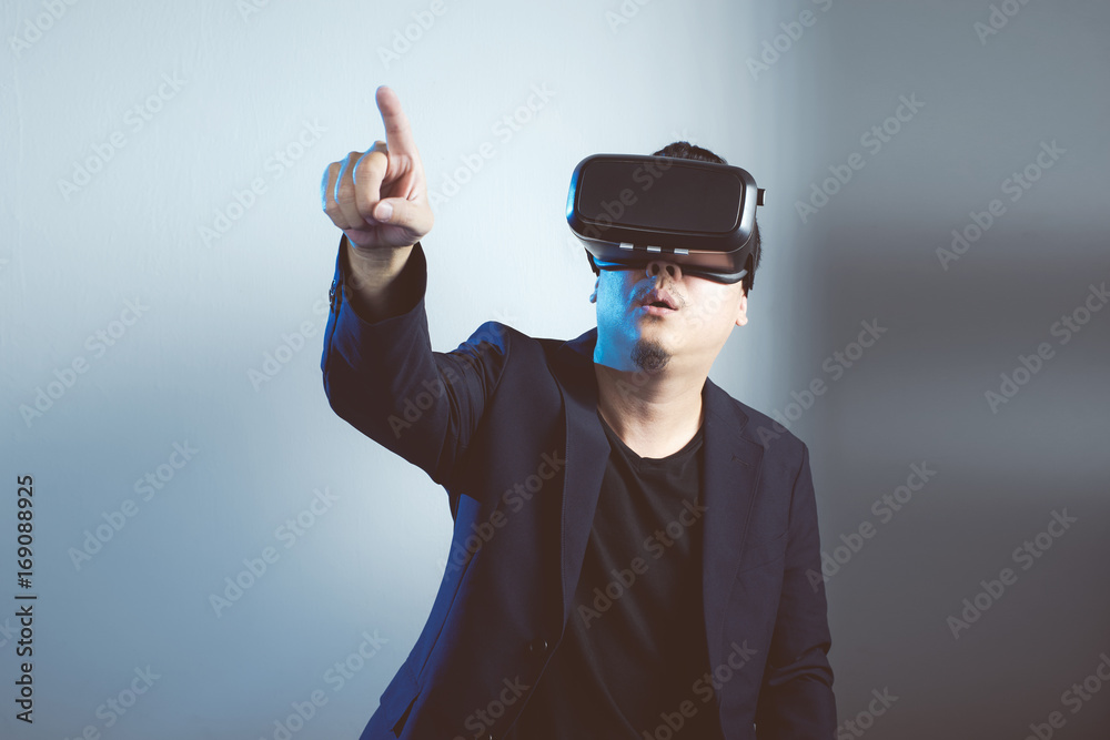 Asian man wearing virtual reality goggle and pointing up . Asian man wearing virtual reality goggle and pointing up .