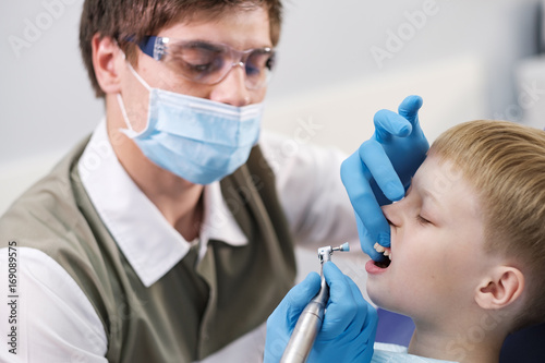 Male dentist examines the teeth of the patient cheerful boy.