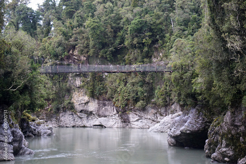 Rope bridge at Hokitika Gorge Walk with river under and forest background