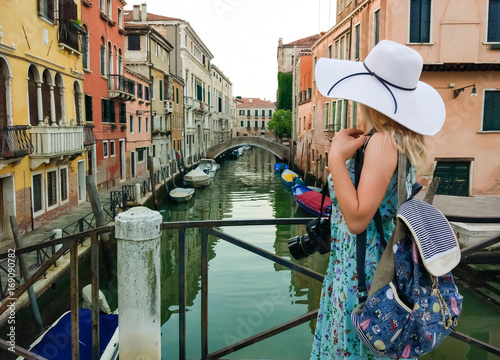 beautiful lady with a big straw hat taking a picture in Venice in Italy