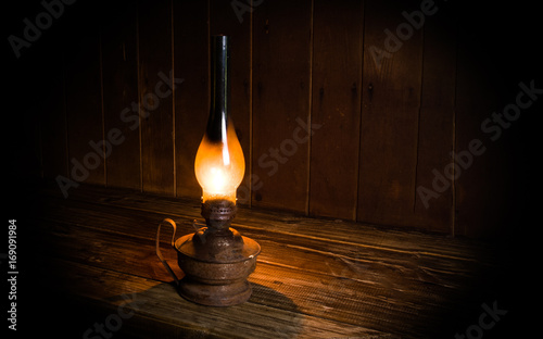 Antique burning paraffin lamp near on the wooden table.