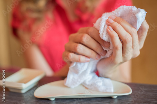 The girl wipes her hands with a hot towel rolled into a roll in a Japanese restaurant before eating