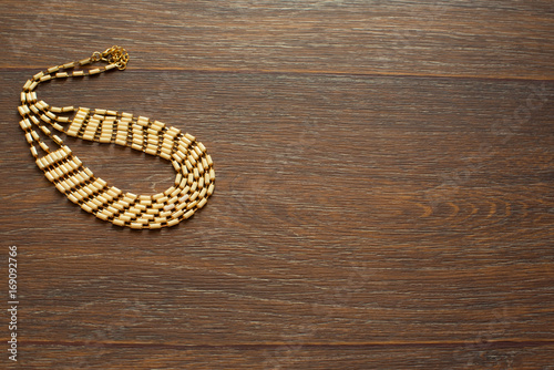 Metal necklace for women on brown wooden background.