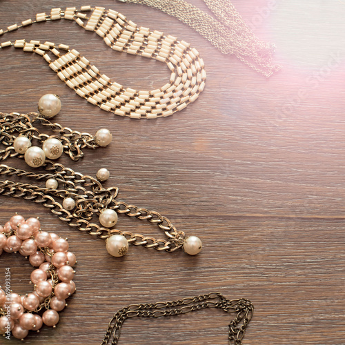 Decorative composition of women's jewelry on wooden dark background.