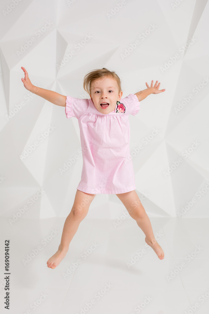 Photo of little girl jumping and raising hands against white background Photo of little girl jumping and raising hands against white background