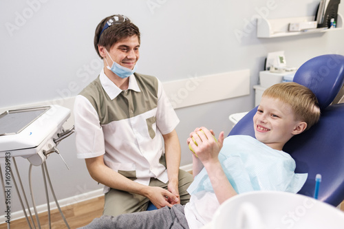 Male dentist examines the teeth of the patient cheerful boy. photo