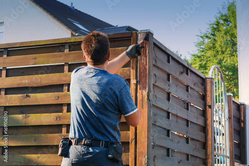 Stroking protective lacquer on a wooden fence