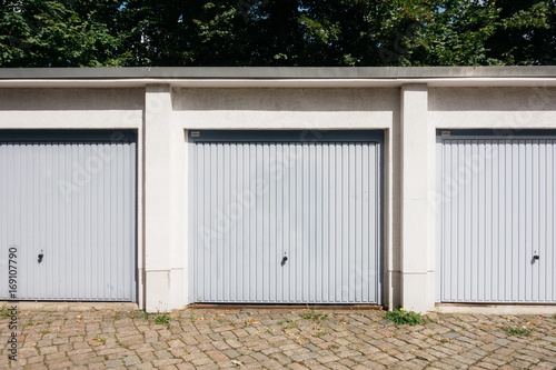 three garages in a row with brown facade and grey doors