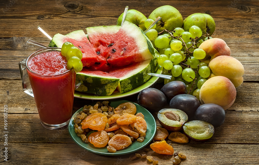 Watermelon smoothies, pieces of watermelon and other fruits on a wooden table
