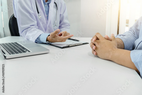 Close up of doctor filling up an history form while consulting patient and recommend treatment methods and how to rehabilitate the body