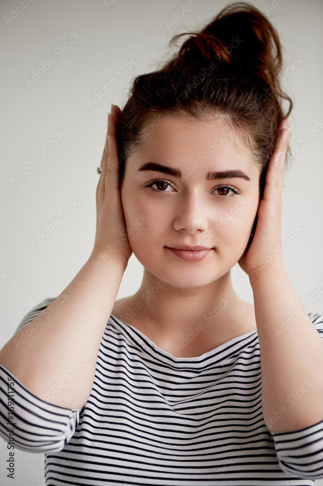 Emotions. Close-up facial portrait. Hear no evil. Girl on a light background covers his ears Emotions. Close-up facial portrait. Hear no evil. Girl on a light background covers his ears