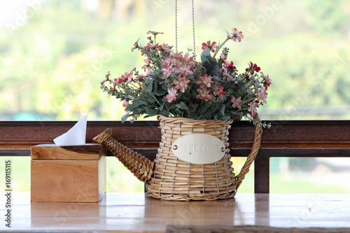 Colorful artificial flowers in rattan watering can. photo