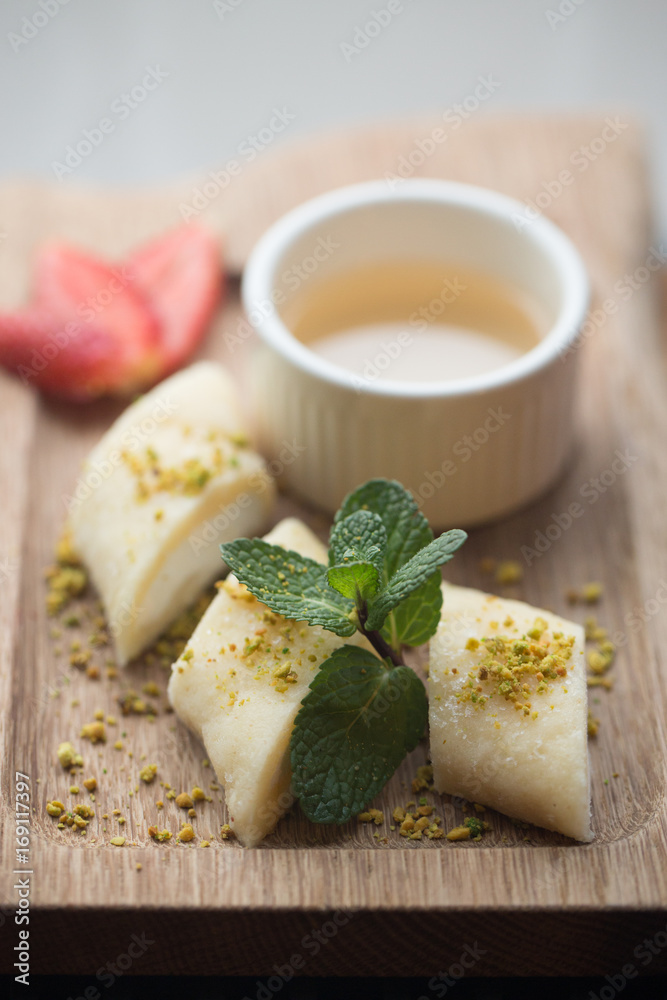 Lebanese dessert halawet jeben with sauce and strawberry on light wood