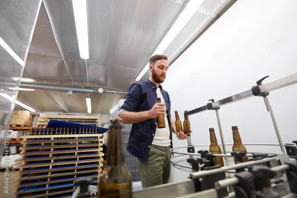 men with bottles on conveyor at craft beer brewery men with bottles on conveyor at craft beer brewery
