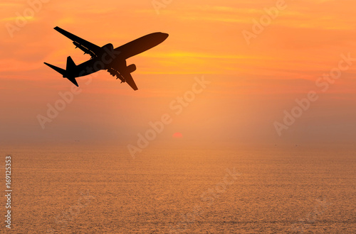 Silhouette passenger airplane flying away in to sky high altitude during sunset