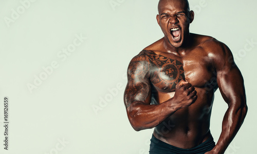 Canvas Print Aggressive bodybuilder screaming against grey background