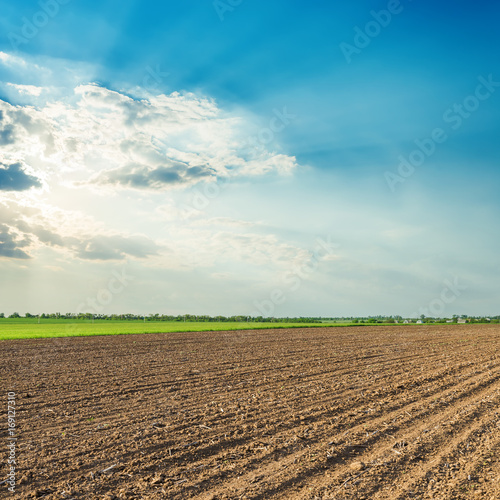 Fotografie, Obraz sun in clouds over black agriculture field
