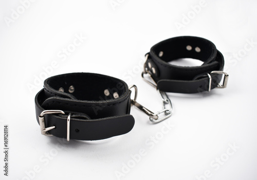 Black Leather Handcuffs with chain isolated on a white background. BDSM erotic tool stock photo. Black leather cuffs. Adult toy images photo