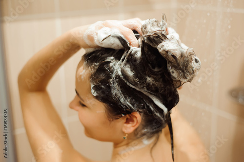 Beautiful woman taking a shower. Washing hair with Shampoo.