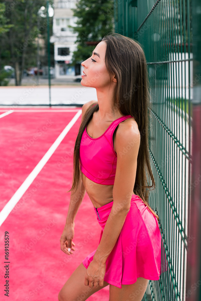 Beautiful sexy young sport woman. Tired girl is standing near the fence.  Fashion of sport fitness girl. Hot workout with a beautiful girl Stock  Photo | Adobe Stock