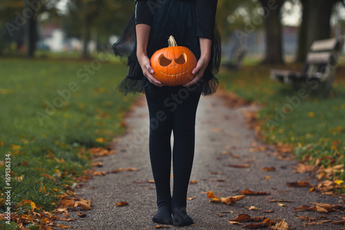 Girl in a black tutu and tights holding a carved pupkin