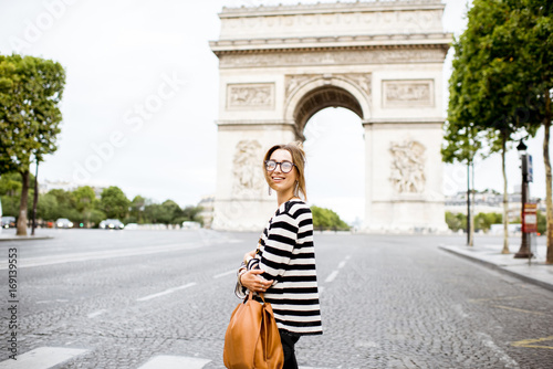 Young business woman in striped sweater crossing street near the famous triumpal arch in Paris