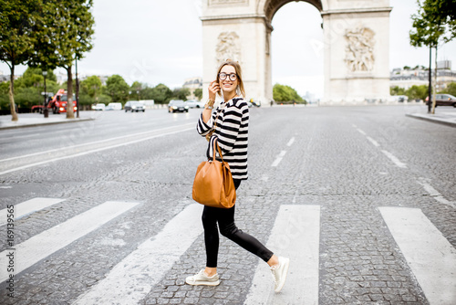 Young business woman in striped sweater crossing street near the famous triumpal arch in Paris