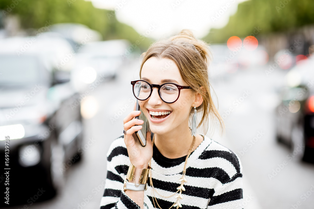 Young and happy woman talking with smart phone standing outdoors on the street with traffic in Paris Young and happy woman talking with smart phone standing outdoors on the street with traffic in Paris