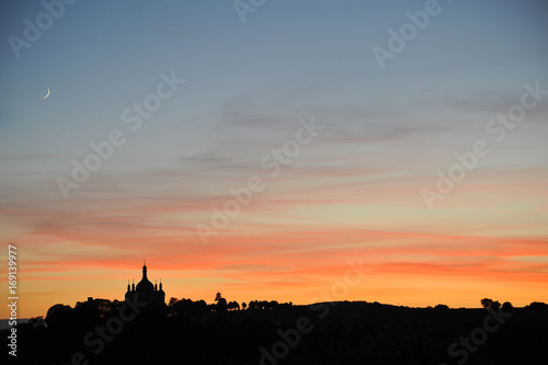 Beautiful sunset - silhouette of the church, trees, forest and young moon in the corner of the photo © xlibes