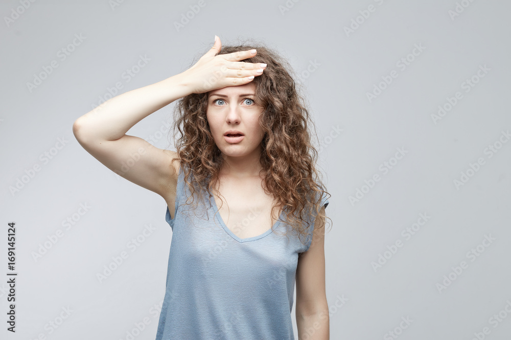 Human face expressions and emotions. Forgetful white-skinned woman holding hand on her head with a painstaking expression as she struggling to remember something. Cute female student slapping forehead