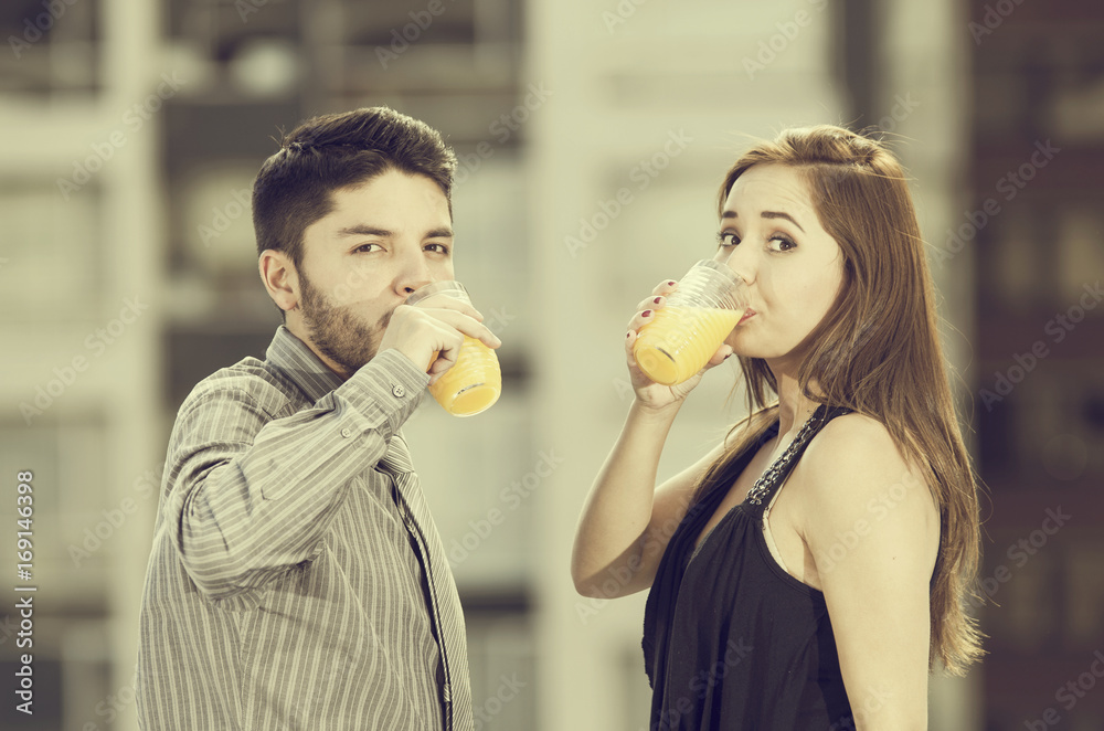 Beautiful young couple drinking a glass of juice and smiling in a blurred background, vintage effect