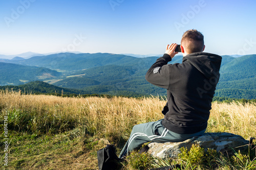 Mężczyzna robi zdjęcia telefonem komórkowym w górach.