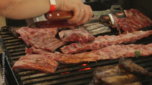 Hands turning meat on grill. Beef ribs. photo