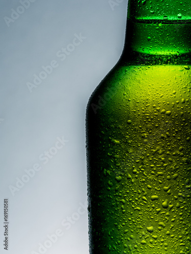 A cold green beer bottle with water drops