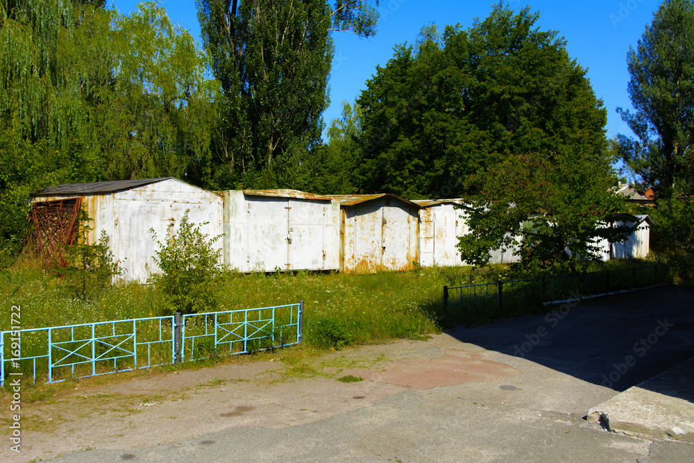 Old abandoned garages near houses. Dead radioactive zone. Consequences of the Chernobyl nuclear disaster, August 2017