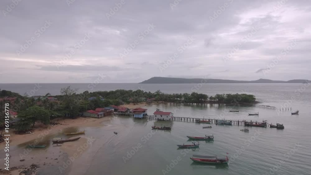 drone view: Fishing village and fishing boats docked at wooden piers under dark cloudy skies. drone view: Fishing village and fishing boats docked at wooden piers under dark cloudy skies.