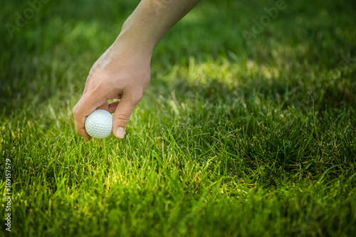 reaching for golf ball in green grass
