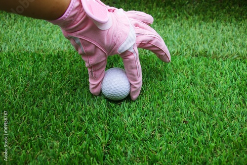 Hand is holding golf ball on green grass