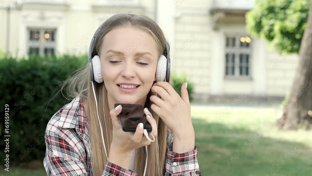 Pretty girl looks happy while chatting on loudspeaker in the park, steadycam shot
Pretty girl looks happy while chatting on loudspeaker in the park, steadycam shot