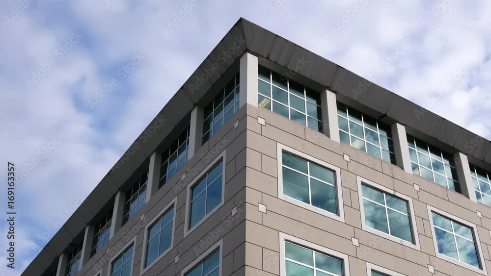 Motion of cloudy sky with illuminated reflected glass facade on modern office building Motion of cloudy sky with illuminated reflected glass facade on modern office building