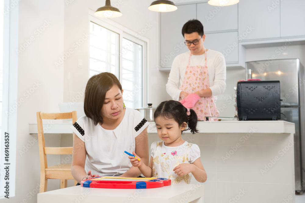 asian mother teaching daughter while father cooking asian mother teaching daughter while father cooking