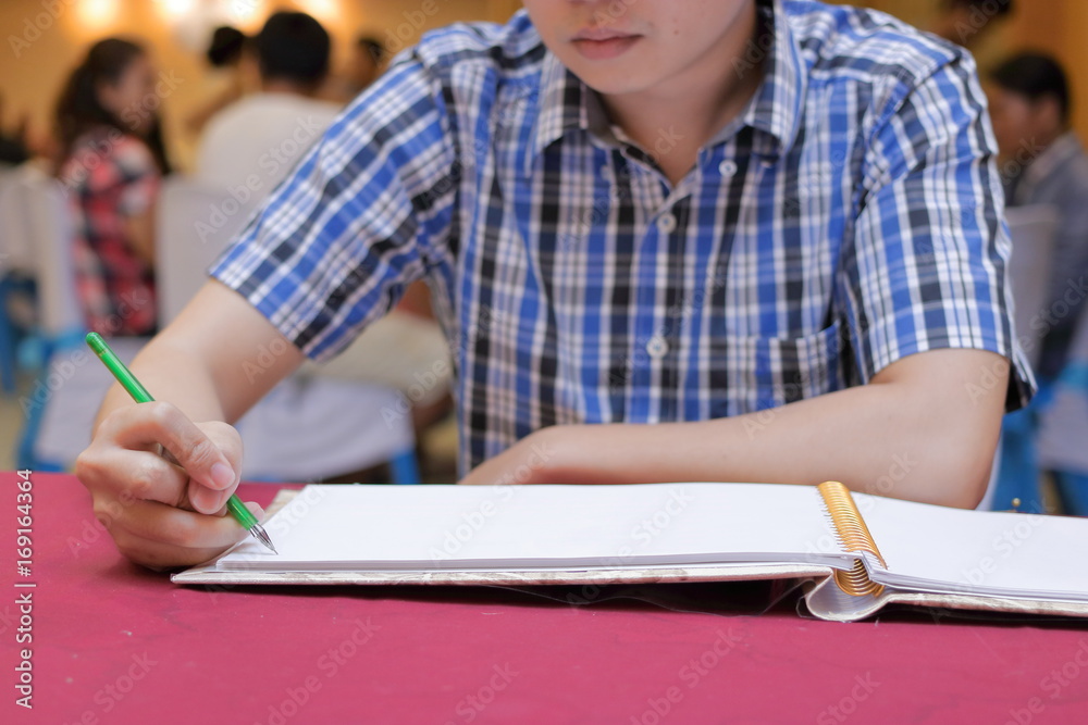 Selective focus on hands of young guest man writing on memory book for blessing word to groom and bride in wedding ceremony Selective focus on hands of young guest man writing on memory book for blessing word to groom and bride in wedding ceremony