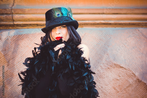 Gothic young woman with long hair at autumn around oldest European church in black dress, vintage accessory and magical mood. Halloween party in big city, black widow style photo