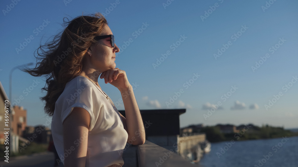 Beautiful girl enjoys the sunset on the waterfront
