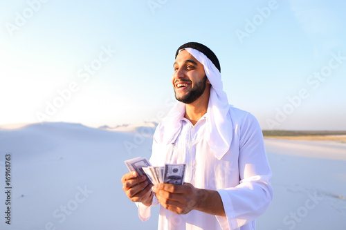 Cuadro en lienzo Successful Arab sheikh considers banknotes and happy, standing i