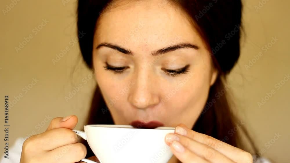 Young beautiful woman drinks a hot drink. The girl enjoys the aroma Young beautiful woman drinks a hot drink. The girl enjoys the aroma